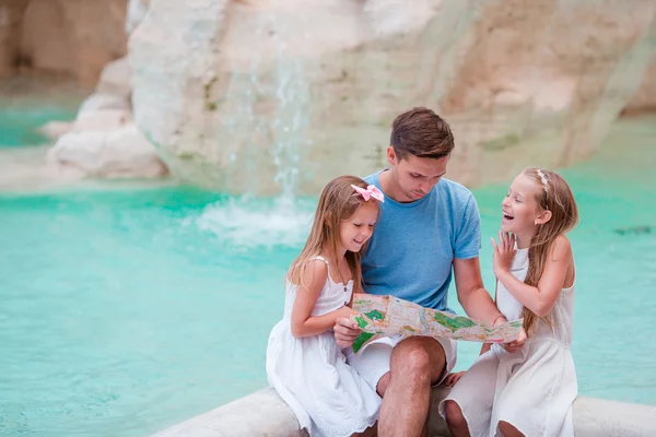 Family with touristic map near Fontana di Trevi, Rome, Italy. Happy father and kids enjoy italian vacation holiday in Europe.