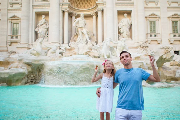 Happy family trowing coins at Trevi Fountain, Rome, Italy for good luck. Happy family enjoy their italian vacation holiday in Europe. Little girl and father making a wish to come back.