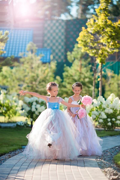 Two adorable girls with beautiful bouquets of roses in hands go to the wedding