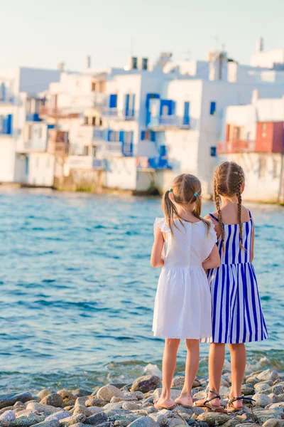 Adorable little girls at Little Venice the most popular tourist area on Mykonos island, Greece. Back view of beautiful kids look at Little Venice background.