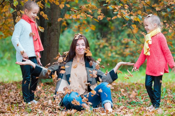 Adorable little girls and young mother in autumn park outdoors