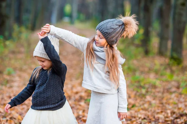 Little adorable girls playing in beautiful autumn park outdoor