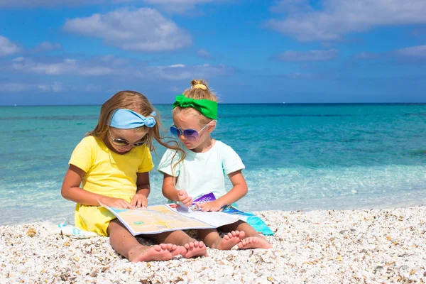Adorable cute girls with big map on tropical beach vacation