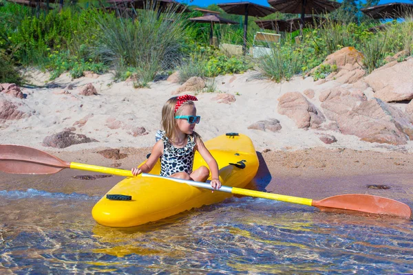 Little cute girl enjoy swimming on yellow kayak in clear turquoise water