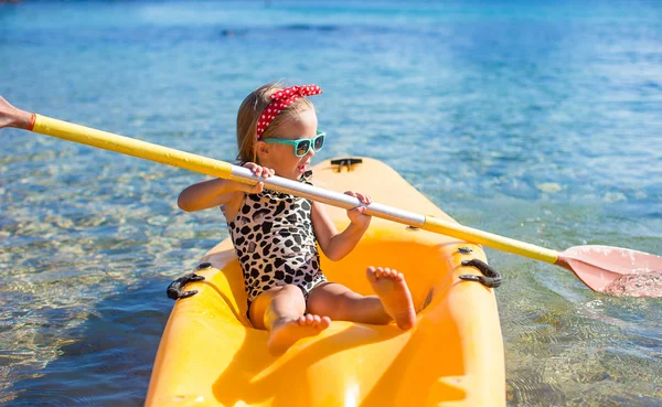 Little cute girl enjoy swimming on yellow kayak in clear turquoise water
