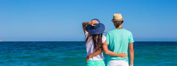 Back view of romantic couple at white beach during tropical vacation