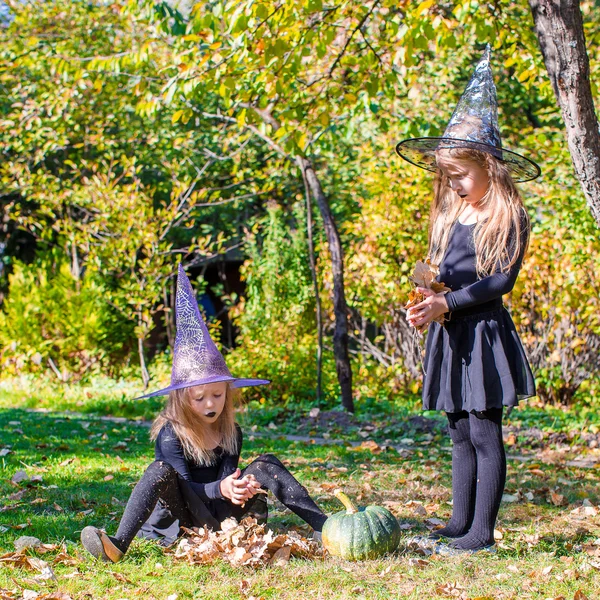 Adorable little girls in witch costume on Halloween outdoors