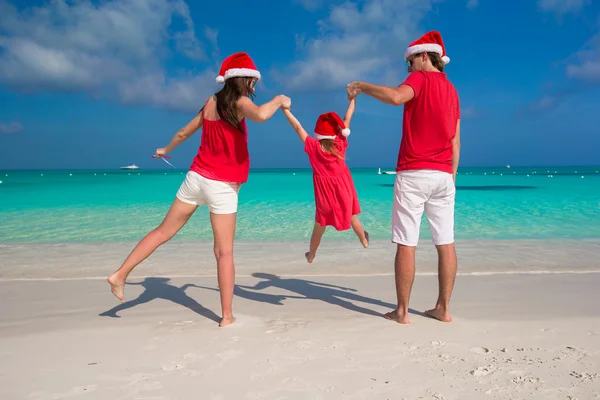 Happy family of three in Christmas Hats during tropical vacation