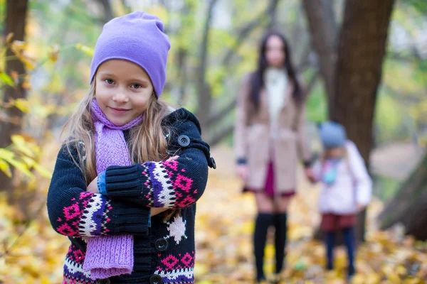 Little girls and young mother in autumn park outdoors