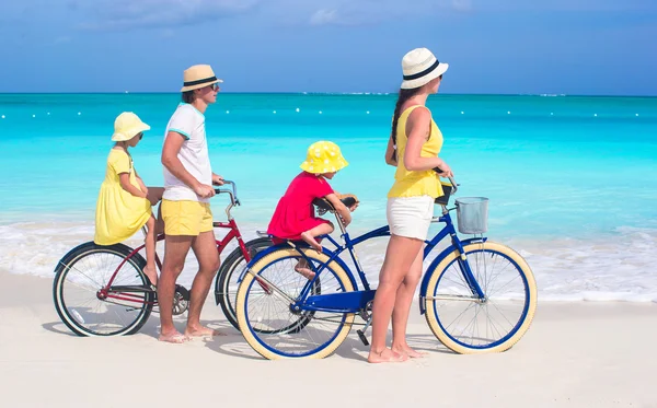 Young family with little kids ride bikes on tropical beach