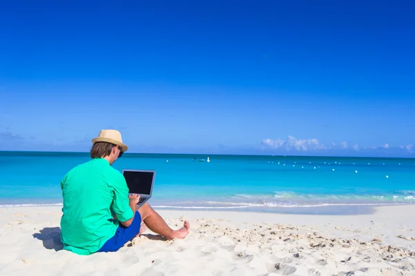 Young man working on laptop at tropical beach