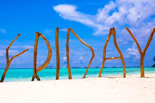 Perfect white sandy beach and turquoise sea on tropical island with wooden letters made Friday word