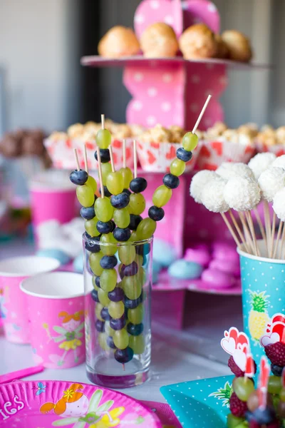 Canape of fruit, white chocolate cake pops and popcorn on sweet childrens table at birthday party