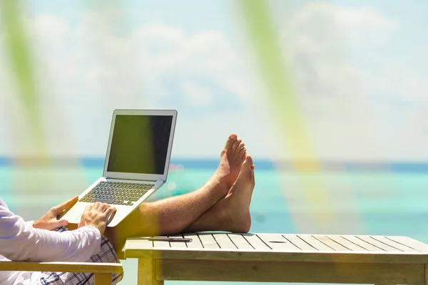 Young man with tablet computer during tropical beach vacation