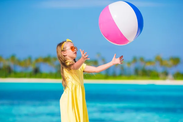 Little adorable girl playing with air ball outdoor on beach