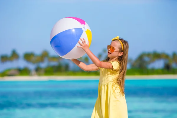 Little adorable girl playing with air ball outdoor on beach