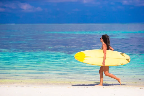 Happy shapely surf woman at white beach with yellow surfboard