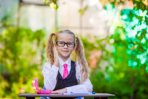 Portrait of happy little school girl in glasses outdoor