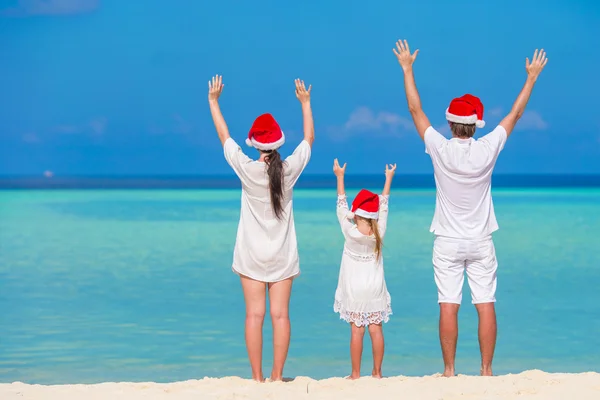 Happy family of three in Santa Hats during Christmas tropical vacation