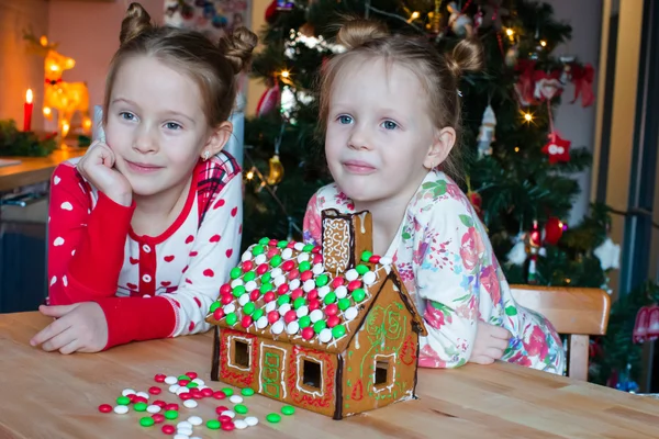 Little adorable girls cooking gingerbread house for Christmas