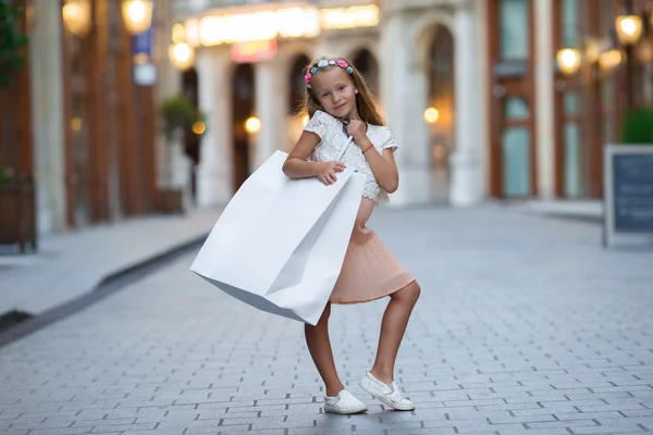 Adorable little girl walking with shopping bags in Paris outdoors