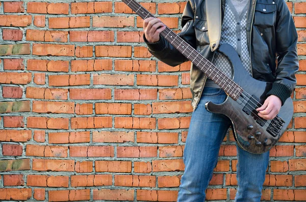Man plays electric guitar on the background brick wall