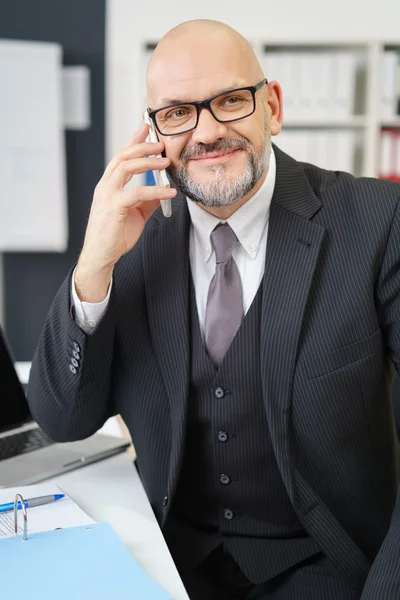 Mature Businessman Talking on Cell Phone in Office