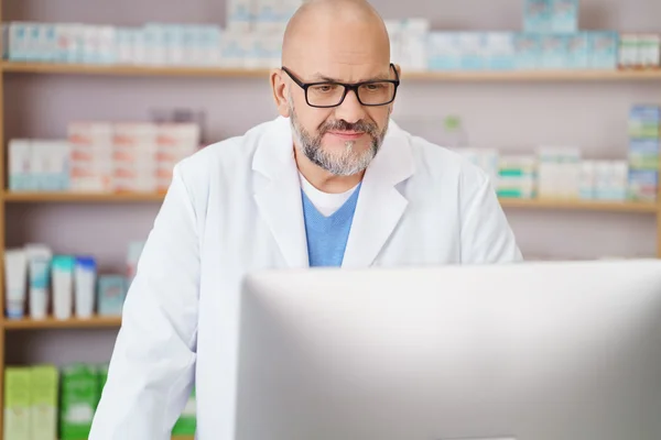 Pharmacist checking information on his computer
