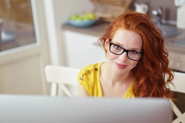Cute red haired woman looking up from computer