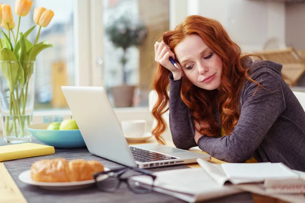 Fatigued woman at breakfast with laptop