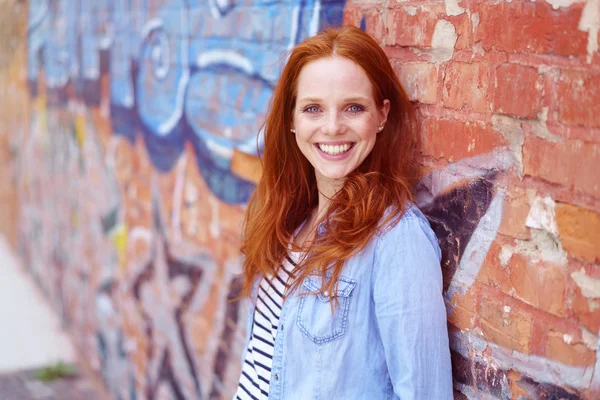 Happy young woman posing against graffiti