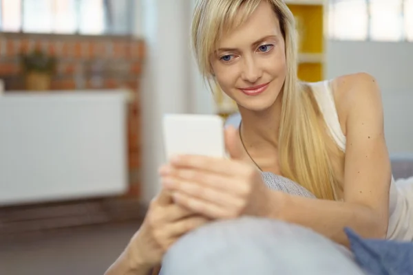 Grinning woman checking messages on cell phone