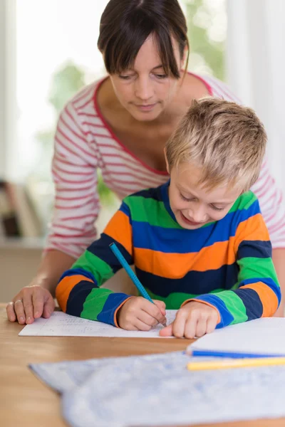 Teacher looking over the shoulder of a young boy