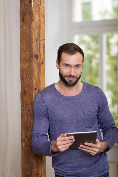 Smiling relaxed man holding a tablet computer