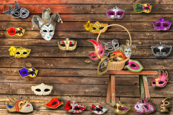 Carnival masks hanging on  wall boards lie on floor and  bench i
