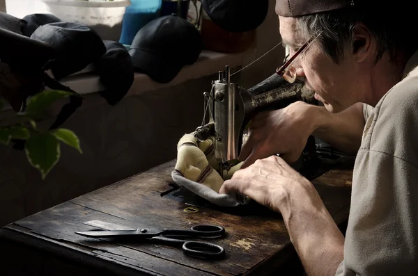 Master making leather goods behind work.