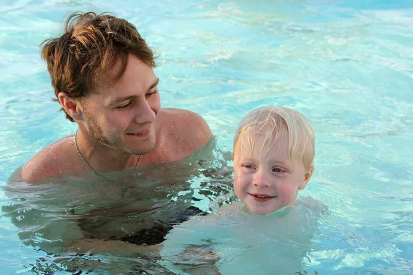 Father Teaching Young Child to Swim in Pool