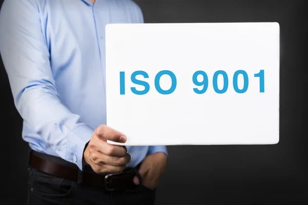 Businessman holding white board with ISO 9001 WORD
