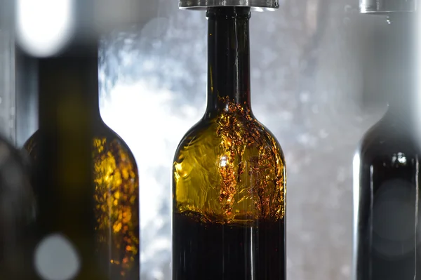 Wine bottle filling along conveyor belt in bottling factory