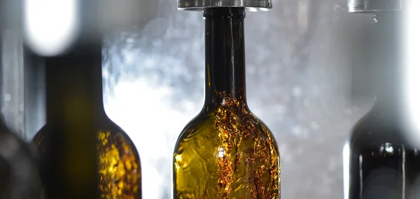 Wine bottle filling along conveyor belt in bottling factory