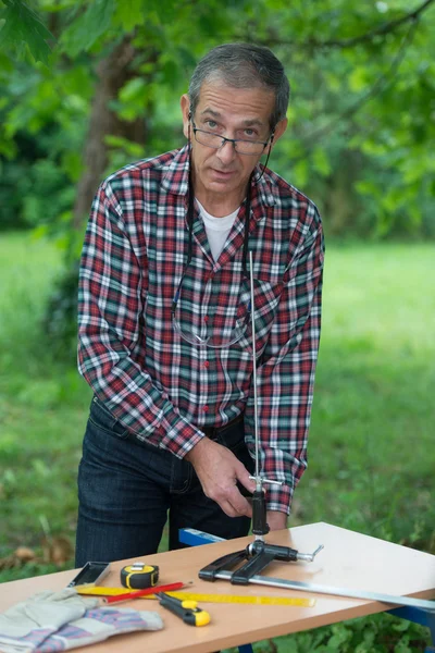 Senior Man screwing on a bench a tight seal