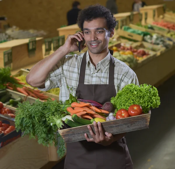 Grocery clerk phoning in produce aisle of supermarket store