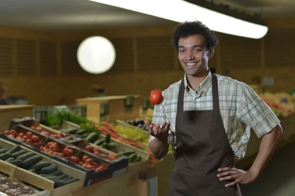 Grocery clerk juggling with tomatoes in supermarket store