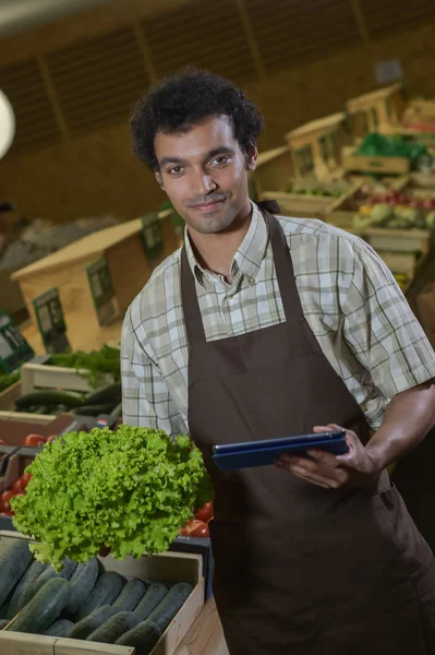Grocery store employee reading inventory list on digital tablet