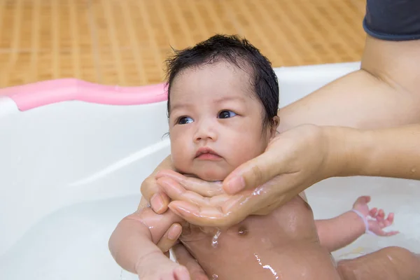Newborn baby taking a bath by mother at home, asian child