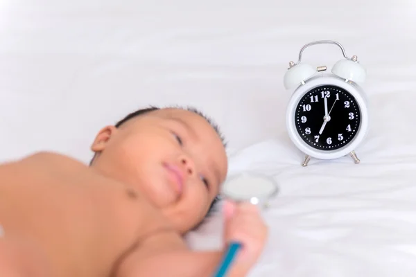 Cute baby girl and alarm clock wake up in the morning