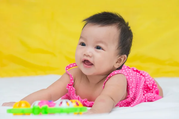 Portrait of cute baby smiling girl on the bed with toy