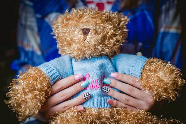 Girl holding a stuffed toy, manicures