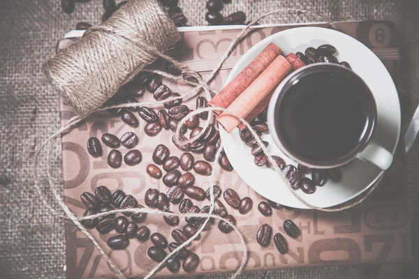 Scattered grains of coffee in a cup on a wooden background