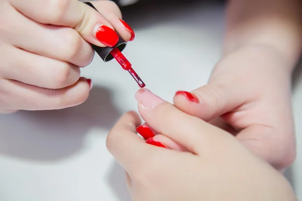 Paint lacquer red nails in beauty salon